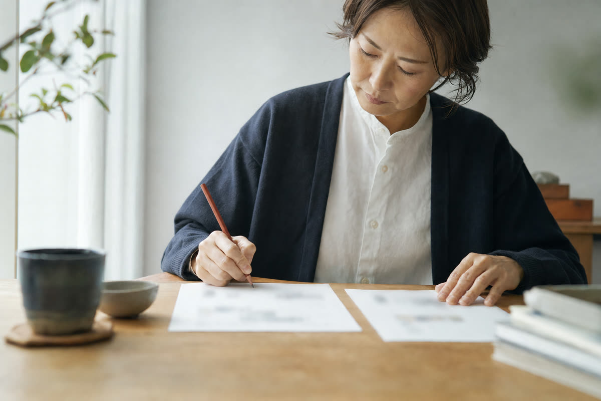 二社の見積書を机に並べ、含まれる項目に印をつけている様子