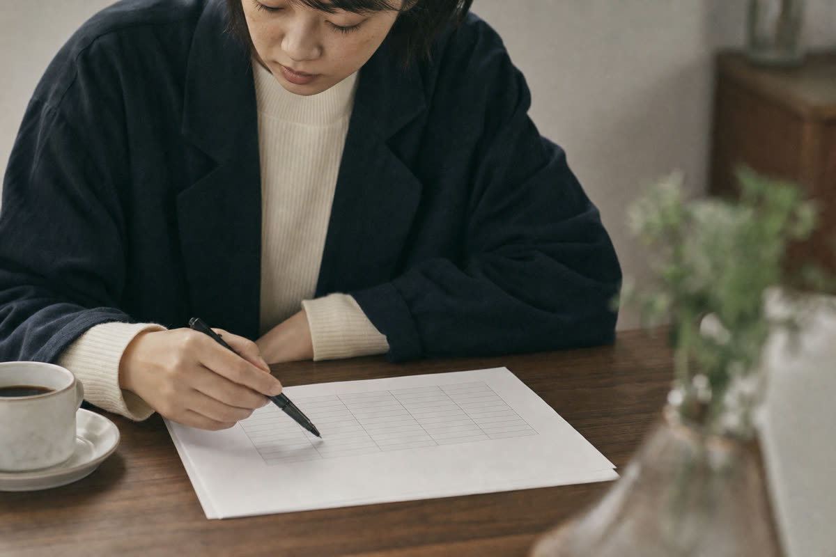 採用費と1年後に残った人数を書き込んだ表をペンで指し示す手元