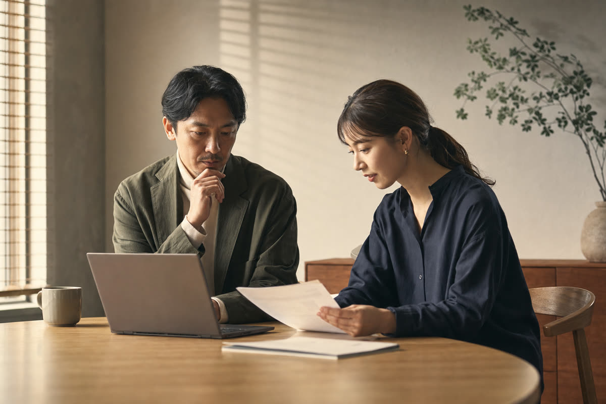 夕方の会議室で、入社と退職の記録を並べて話し合う経営者と人事担当者