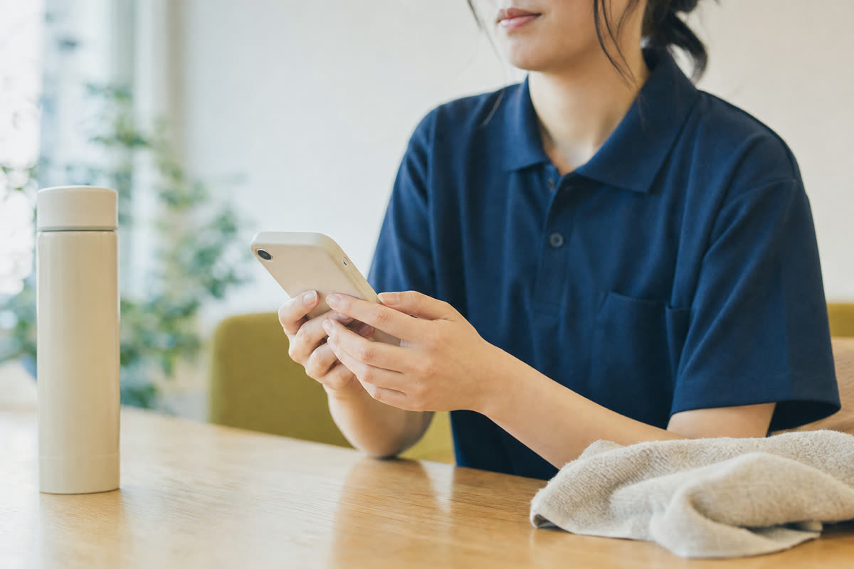 休憩室でスマートフォンのLINEからアンケートに答える介護スタッフの手元