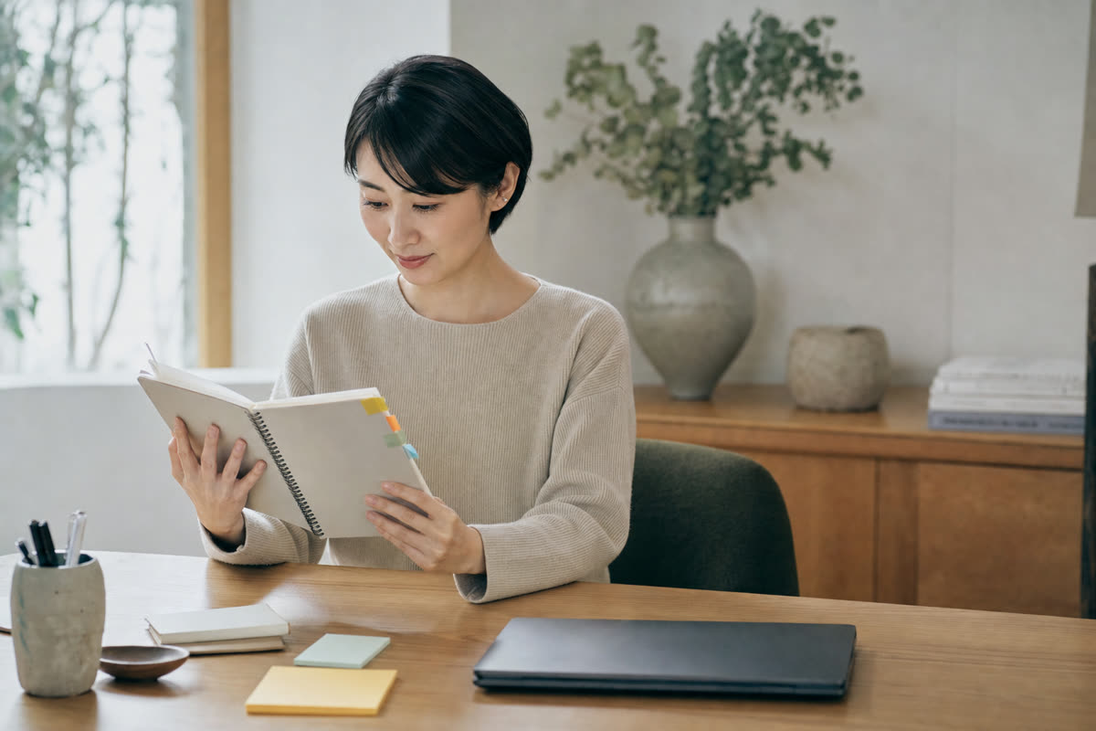 求人媒体ごとの採用記録を並べたノートを見比べる採用担当者