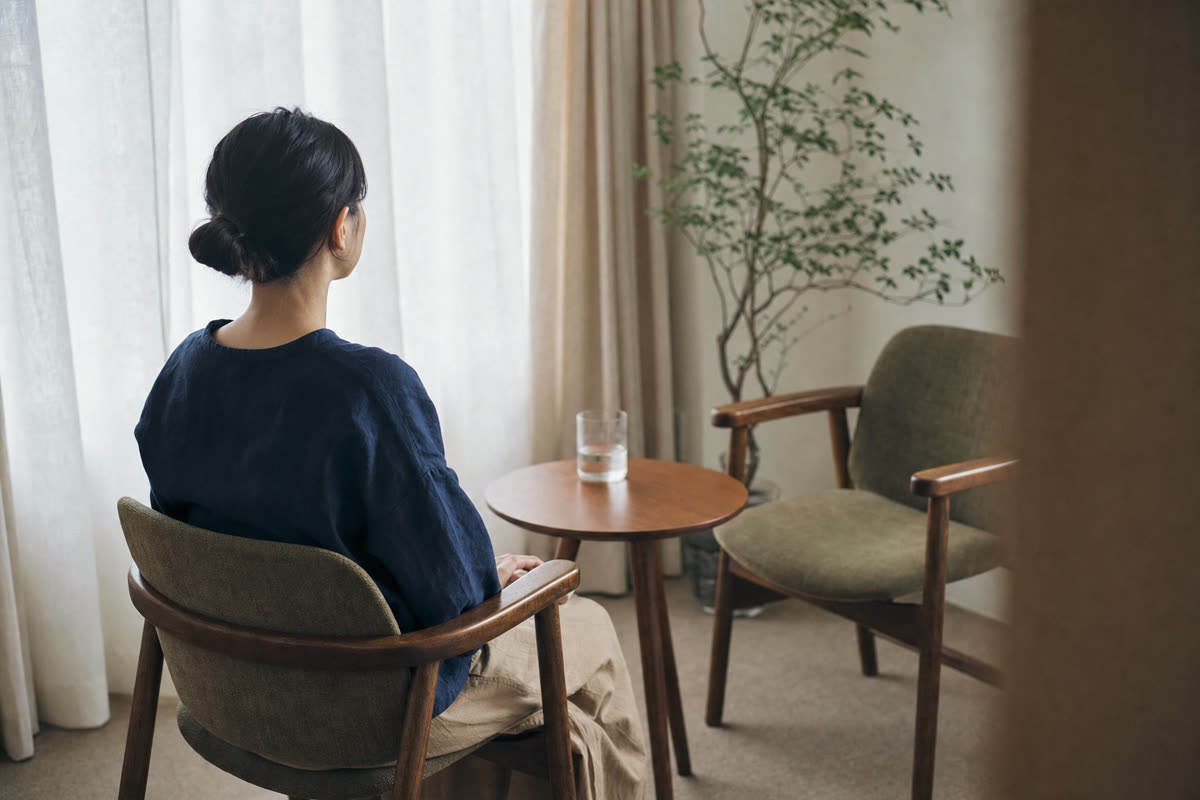 静かな相談室で、医師との面談を待つ社員の後ろ姿と窓の光