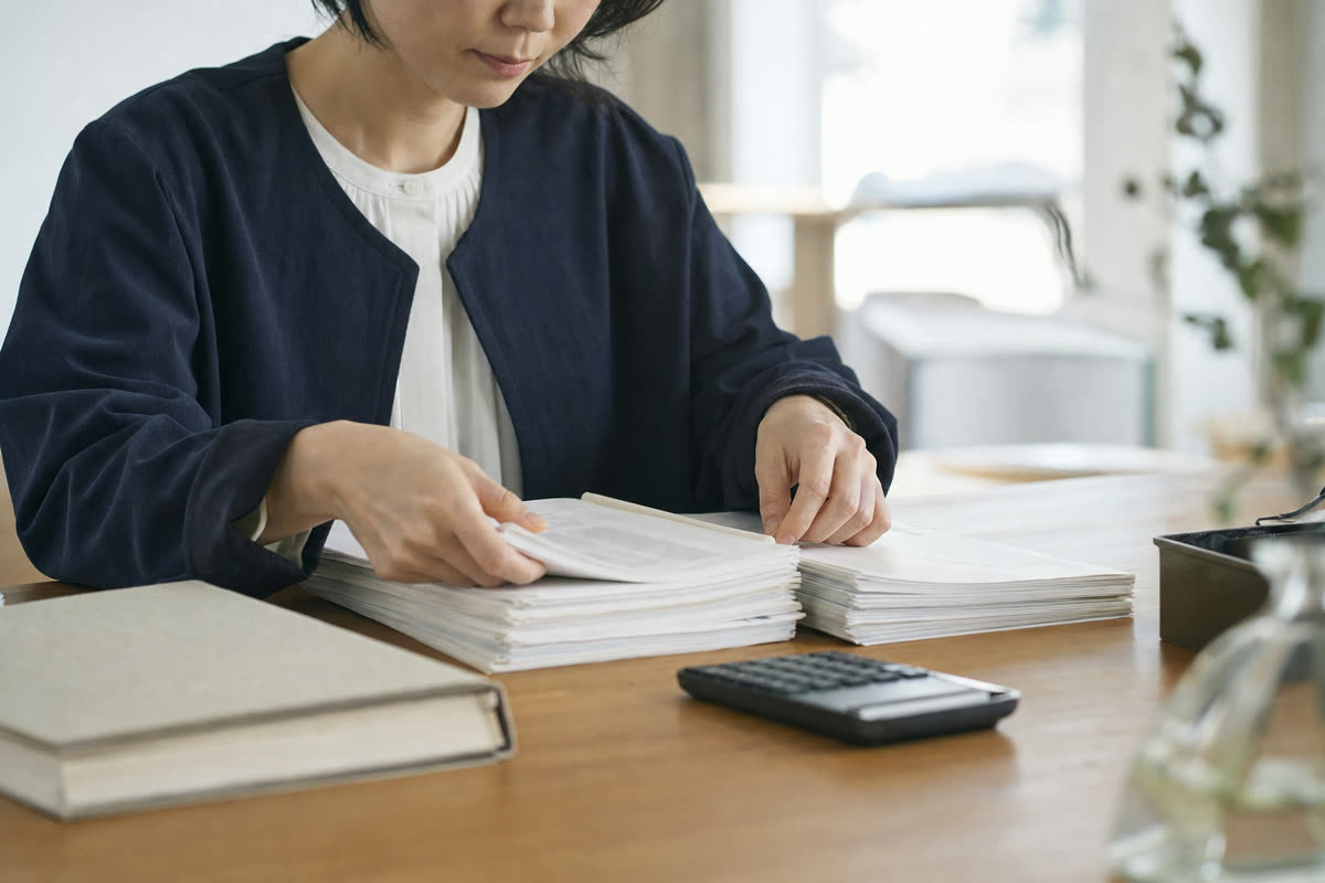 雇用保険の資格喪失の記録と退職届の控えを並べて、件数を数える総務担当者の手元
