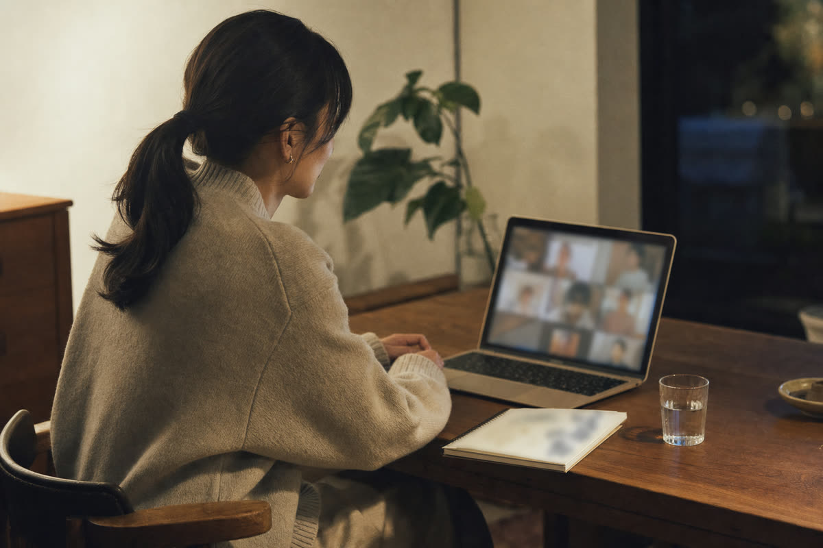 静かな個室で、外部の相談員がオンラインで社員の話を聞いているノートパソコンの画面の手前