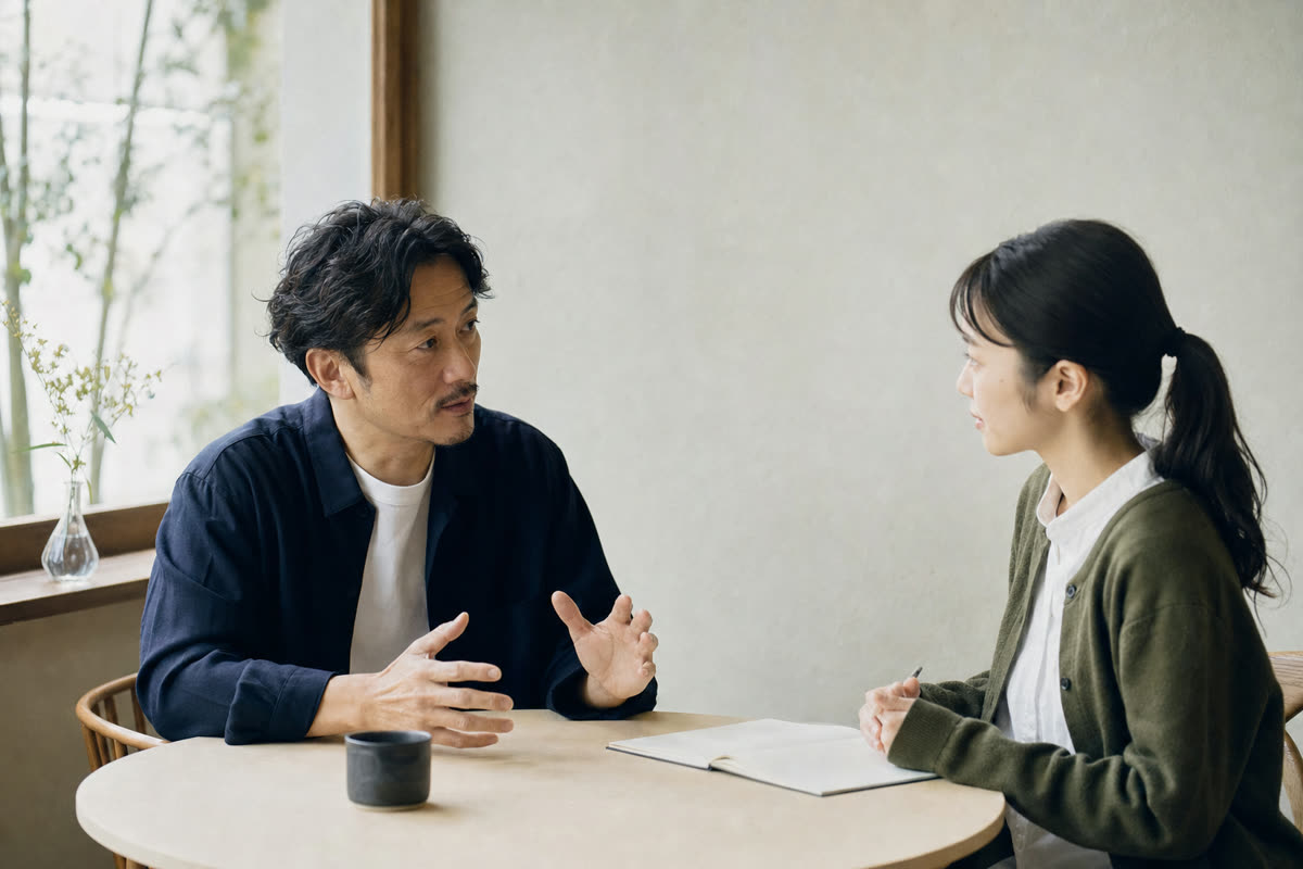 上司と部下が落ち着いた雰囲気で仕事の進め方を話し合う小さなオフィス