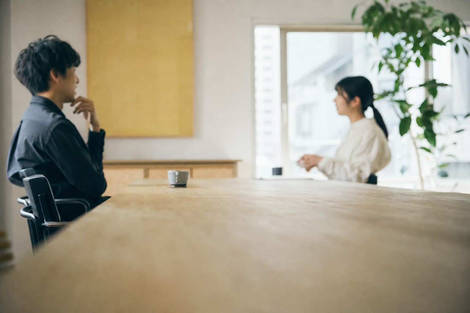 事業所の事務室で、会議用のまとめを見ながら話し合う管理者たち(イメージ)
