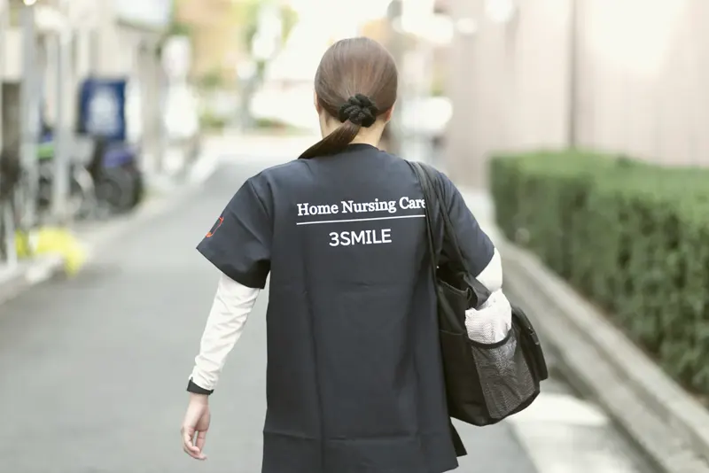 訪問看護の制服で歩くスタッフの後ろ姿（関連会社3SMILE）